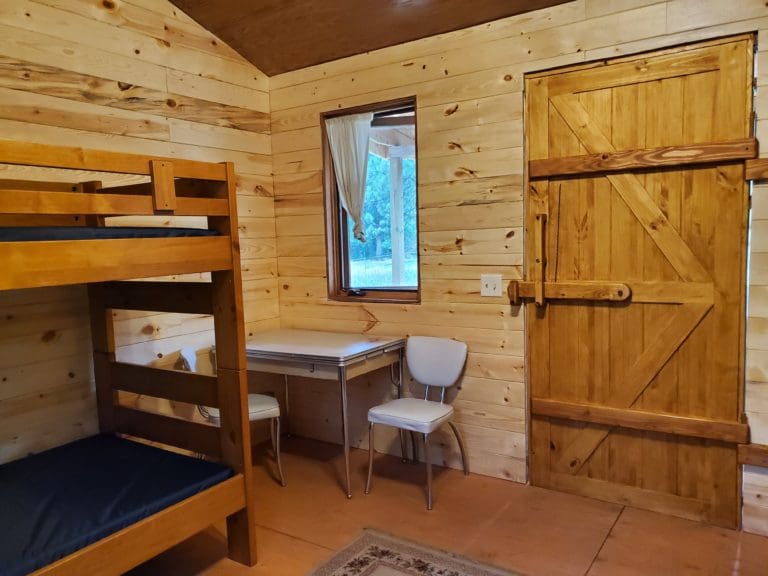 Interior of cabin 2 with front door, seating, table, and bunk beds